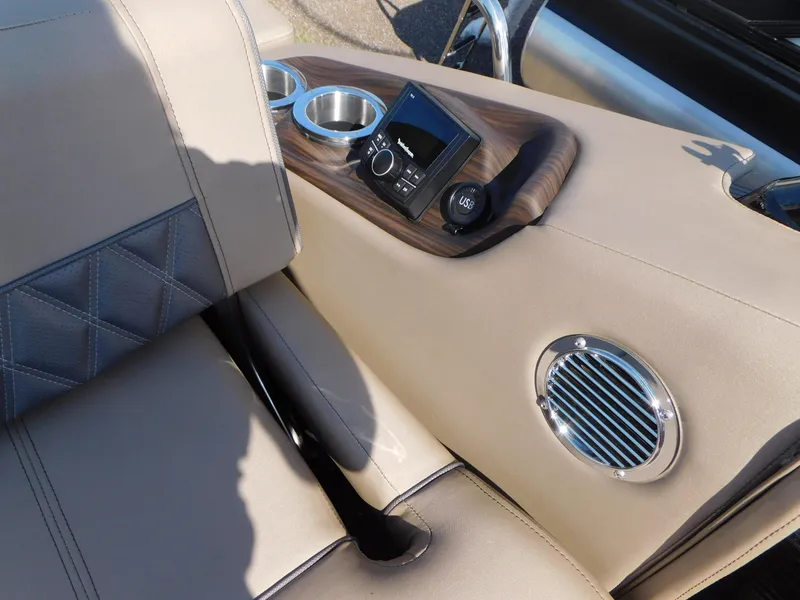 Slide: The Image of 2023 Bennington 23RSBA boat interior with beige seating, cup holders, and audio controls. - 12