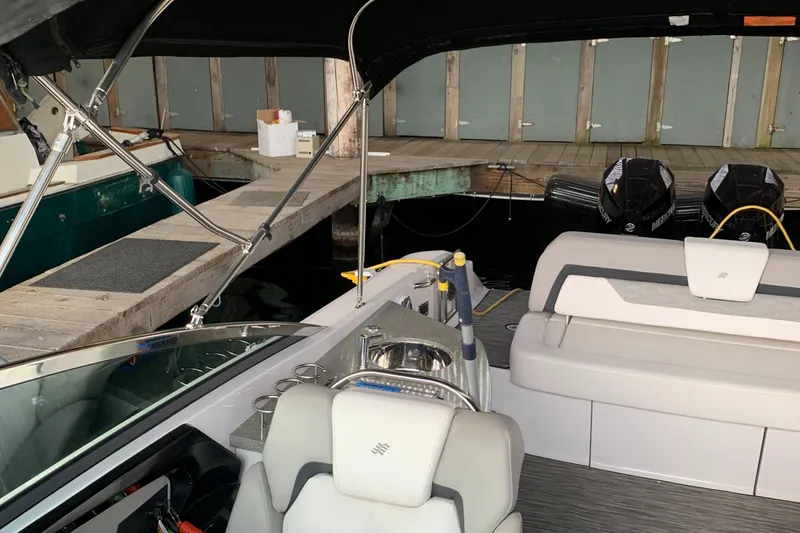Slide: The Image of 2019 Four Winns H290 OB boat interior at dock, featuring seating and dual outboard motors. - 14