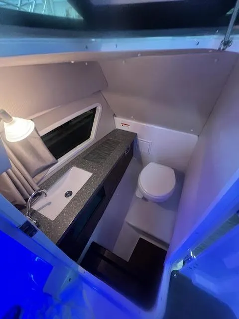 Slide: The Image of 2019 Four Winns H290 OB boat interior bathroom with sink and toilet. - 29