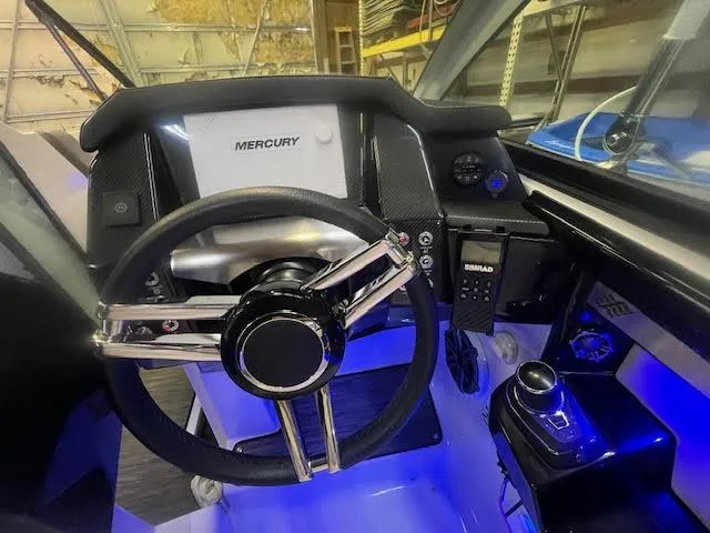 Slide: The Image of 2019 Four Winns H290 OB boat dashboard with Mercury controls and illuminated steering wheel. - 30