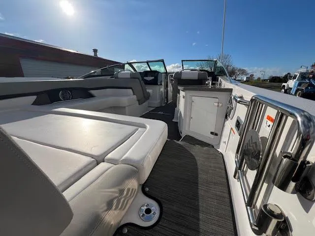 Slide: The Image of 2019 Four Winns H290 OB boat interior with seating and kitchenette under sunny sky. - 37