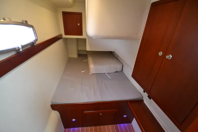 Slide: The Image of 2022 ArrowCat 42 Coupe cabin interior with bed and wooden storage cabinets. - 16