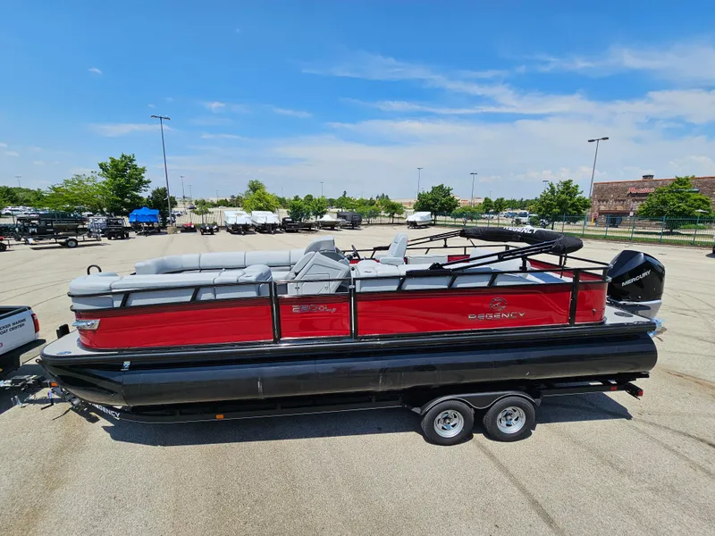 Slide: The Image of 2023 Regency 250 DL3 pontoon boat with red and black exterior on a trailer. - 2