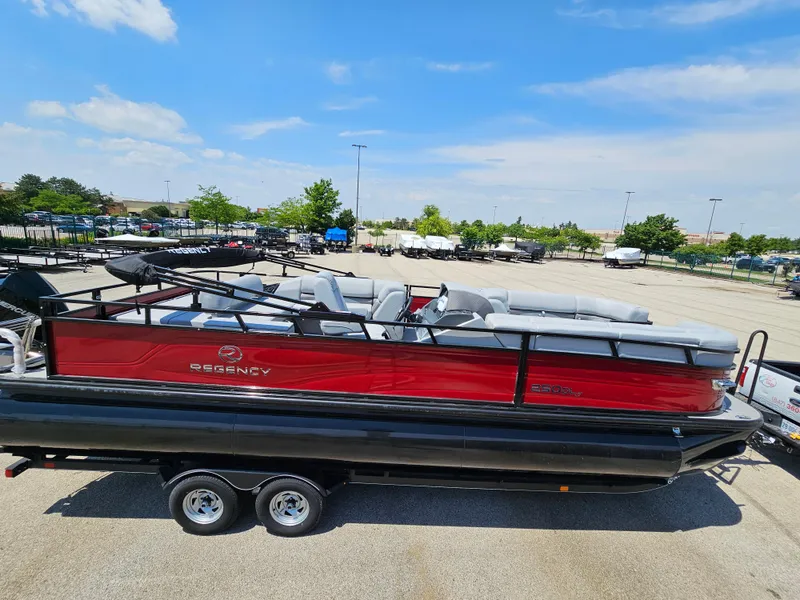 Slide: The Image of 2023 Regency 250 DL3 pontoon boat with red and black exterior in a parking lot. - 3