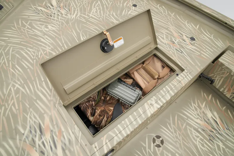 Slide: The Image of 2023 Tracker Grizzly 1654 T Sportsman storage compartment with camo gear and accessories. - 20
