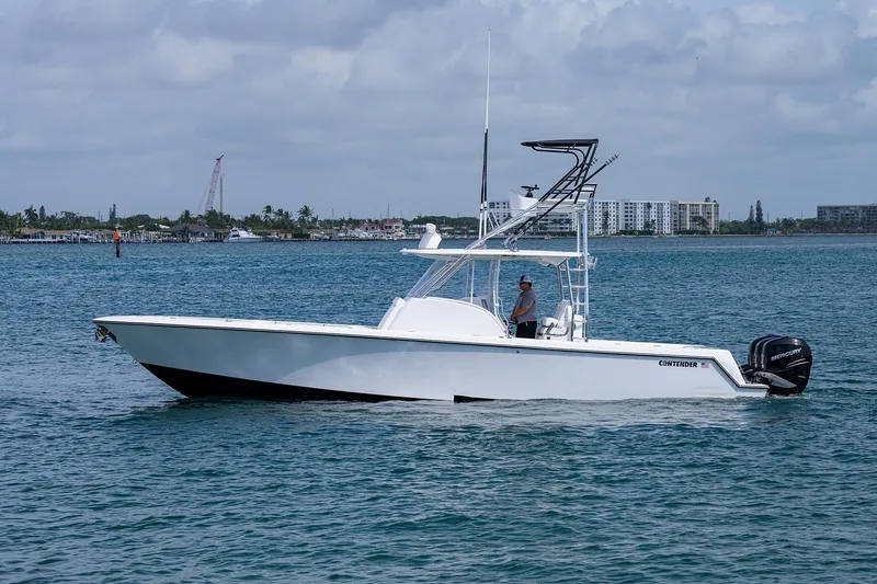 Slide: The Image of Contender 39FA 2025 model boat cruising on a calm sea with a cityscape background. - 0