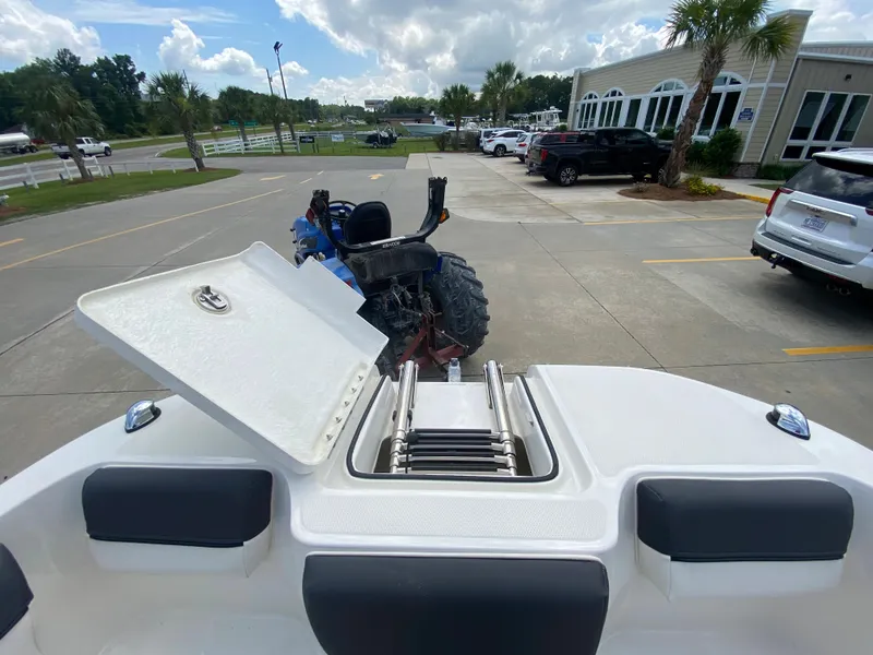 Slide: The Image of 2022 Bayliner DX2000 boat with open storage compartment and ladder, parked outdoors. - 27