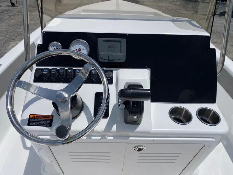 Slide: The Image of 2023 Savannah 190IS boat console with steering wheel, gauges, and cup holders. - 6
