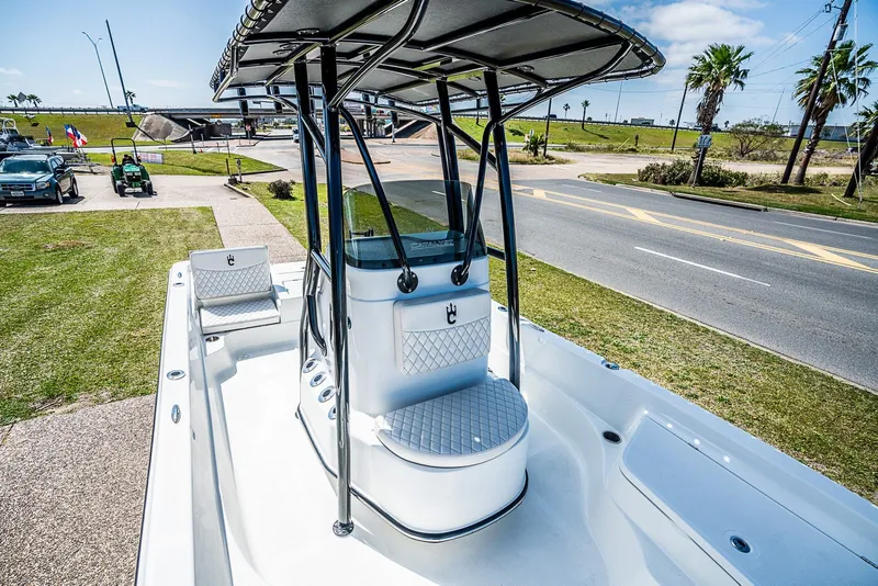 Slide: The Image of 2021 Catalyst 2300 BAY boat interior with seating and console, parked near a road. - 15