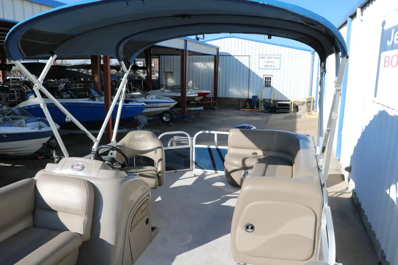 Slide: The Image of 2021 Ranger RP200C pontoon boat with canopy and beige seating at a marina. - 20