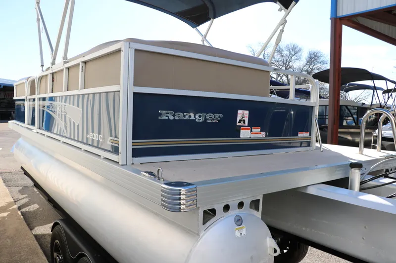 Slide: The Image of 2021 Ranger RP200C pontoon boat with blue and beige exterior, docked at marina. - 7
