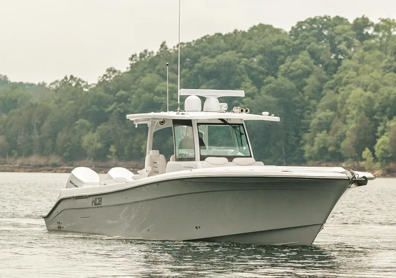 Slide: The Image of 2023 HCB 39 Speciale boat cruising on a calm lake with a forested background. - 10