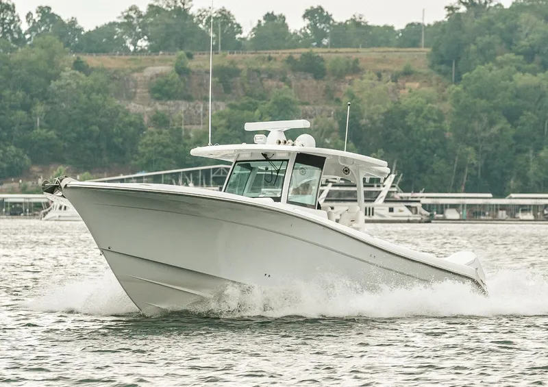 Slide: The Image of 2023 HCB 39 Speciale boat cruising on a lake with lush green trees in the background. - 11