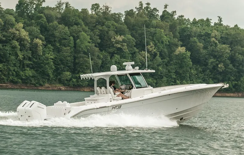 Slide: The Image of 2023 HCB 39 Speciale boat cruising on a lake with forested shoreline. - 12