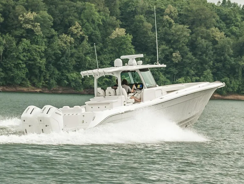 Slide: The Image of 2023 HCB 39 Speciale boat cruising on a lake with lush green forest background. - 13