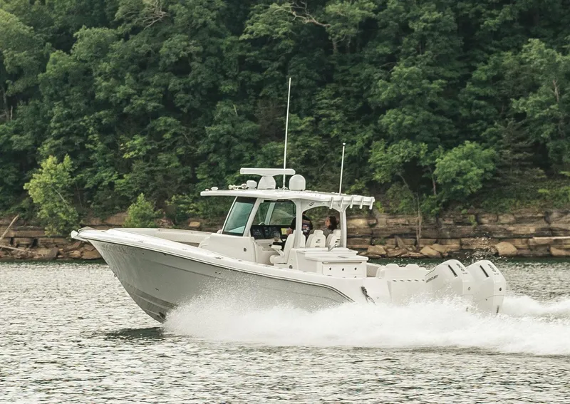 Slide: The Image of 2023 HCB 39 Speciale boat cruising on a lake with lush green trees in the background. - 14