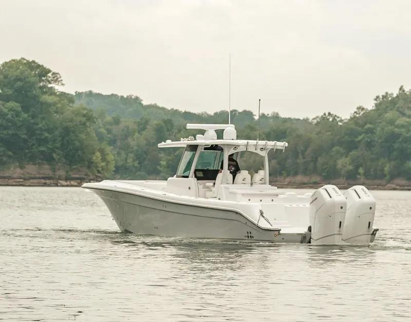 Slide: The Image of 2023 HCB 39 Speciale boat cruising on a calm lake with forested shoreline. - 2