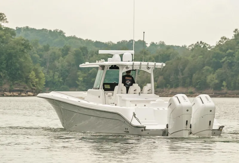 Slide: The Image of 2023 HCB 39 Speciale boat cruising on a lake with forested shoreline. - 3