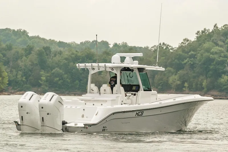 Slide: The Image of 2023 HCB 39 Speciale boat cruising on a lake with forested background. - 6