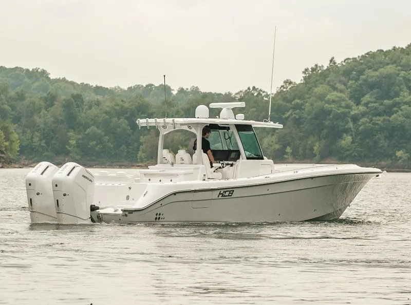 Slide: The Image of 2023 HCB 39 Speciale boat cruising on a lake with forested background. - 7