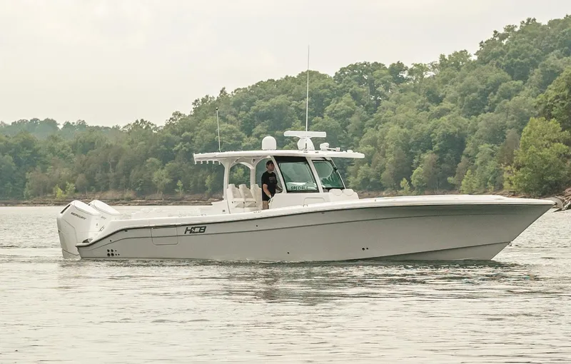 Slide: The Image of 2023 HCB 39 Speciale boat cruising on a calm lake with forested shoreline. - 8