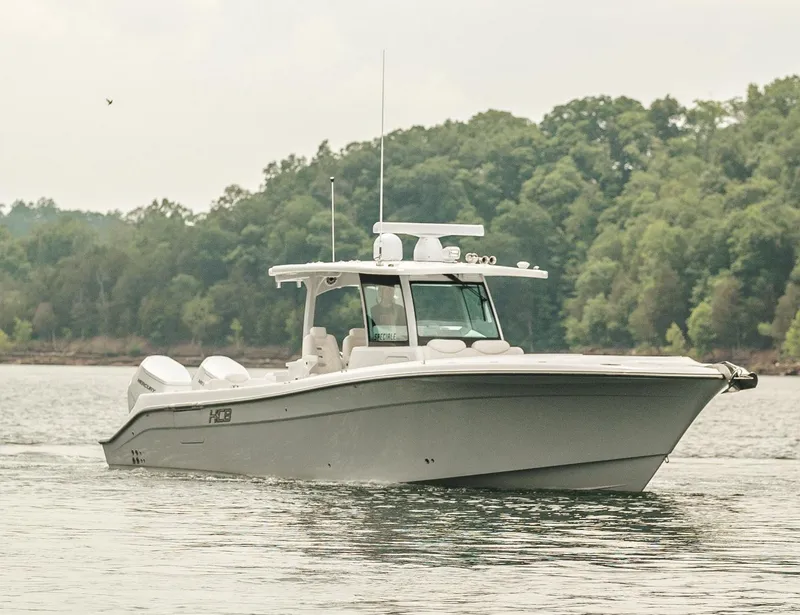 Slide: The Image of 2023 HCB 39 Speciale boat cruising on a lake with forested background. - 9