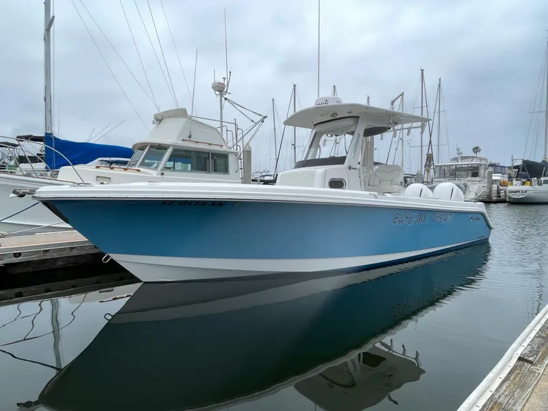 The Image of 2021 Edgewater 262CC boat on trailer, blue hull, parked near warehouse. - 0