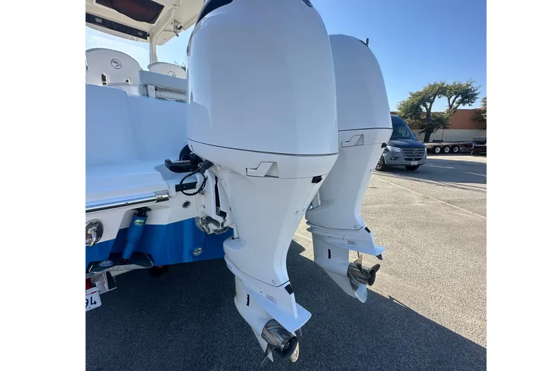 Slide: The Image of Twin outboard motors on a 2021 Edgewater 262CC boat, parked outdoors. - 21