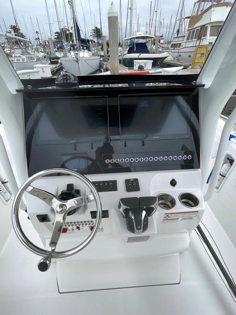 Slide: The Image of 2021 Edgewater 262CC boat docked at a marina, showcasing its spacious deck and seating area. - 8