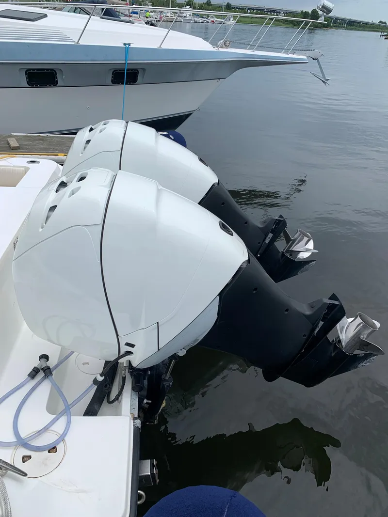 Slide: The Image of Twin outboard motors on a 2009 Mako 284 Express boat docked in a marina. - 23