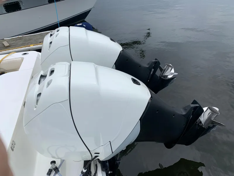 Slide: The Image of Twin outboard motors on a 2009 Mako 284 Express boat docked by the water. - 24