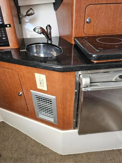 Slide: The Image of 2009 Mako 284 Express boat interior with sink, stove, and fridge. - 29