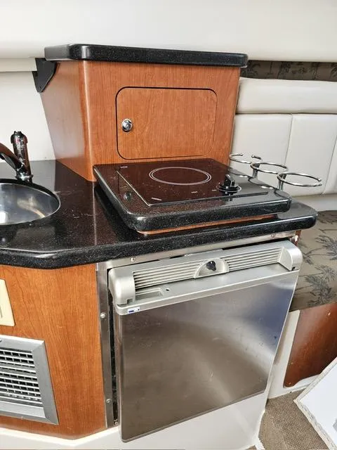 Slide: The Image of Compact kitchen area in a 2009 Mako 284 Express boat with stove and mini fridge. - 34