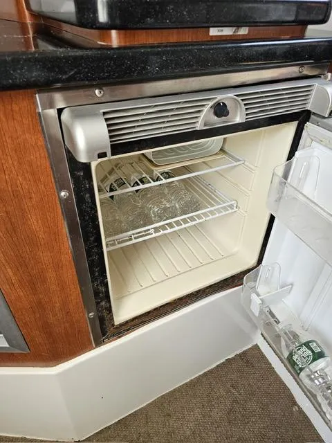 Slide: The Image of 2009 Mako 284 Express boat interior with open mini fridge. - 36