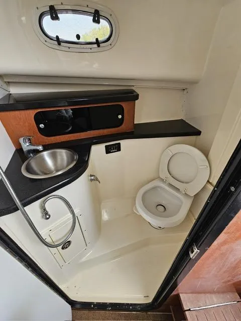 Slide: The Image of 2009 Mako 284 Express boat bathroom with sink, toilet, and storage cabinet. - 37