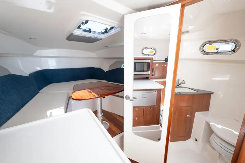 Slide: The Image of 2024 Pursuit OS 325 Offshore cabin interior with kitchenette and seating area. - 10