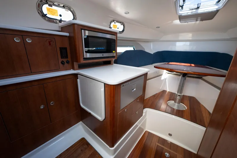 Slide: The Image of 2024 Pursuit OS 325 Offshore cabin with wood cabinetry and seating area. - 13