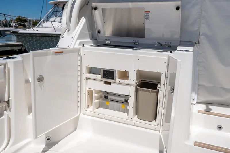 Slide: The Image of 2024 Pursuit OS 325 Offshore boat storage compartment with open doors. - 14