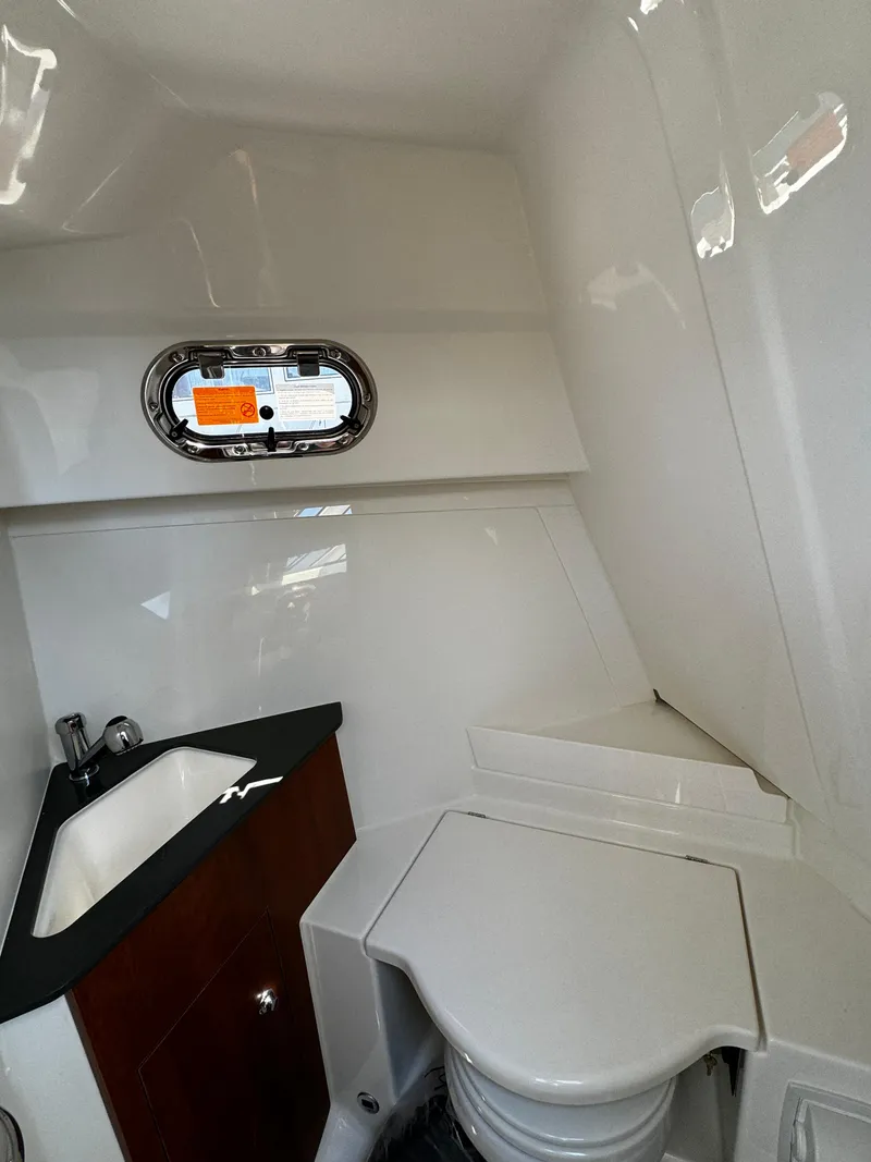 Slide: The Image of 2024 Pursuit OS 325 Offshore boat bathroom with sink and porthole window. - 20
