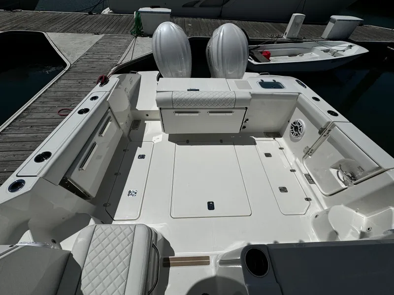 Slide: The Image of 2024 Pursuit OS 325 Offshore boat interior with dual engines, docked at marina. - 5