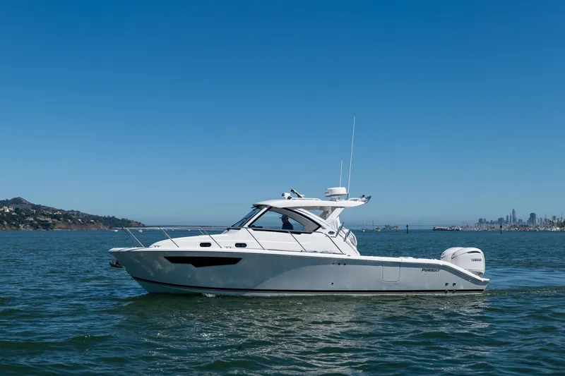 Slide: The Image of 2024 Pursuit OS 325 Offshore boat cruising on open water under clear blue skies. - 6