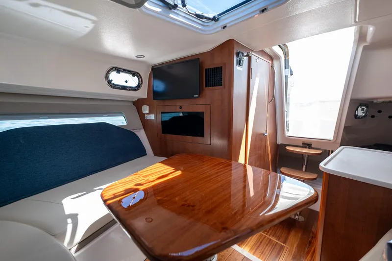 Slide: The Image of 2024 Pursuit OS 325 Offshore cabin interior with wood table and seating. - 9