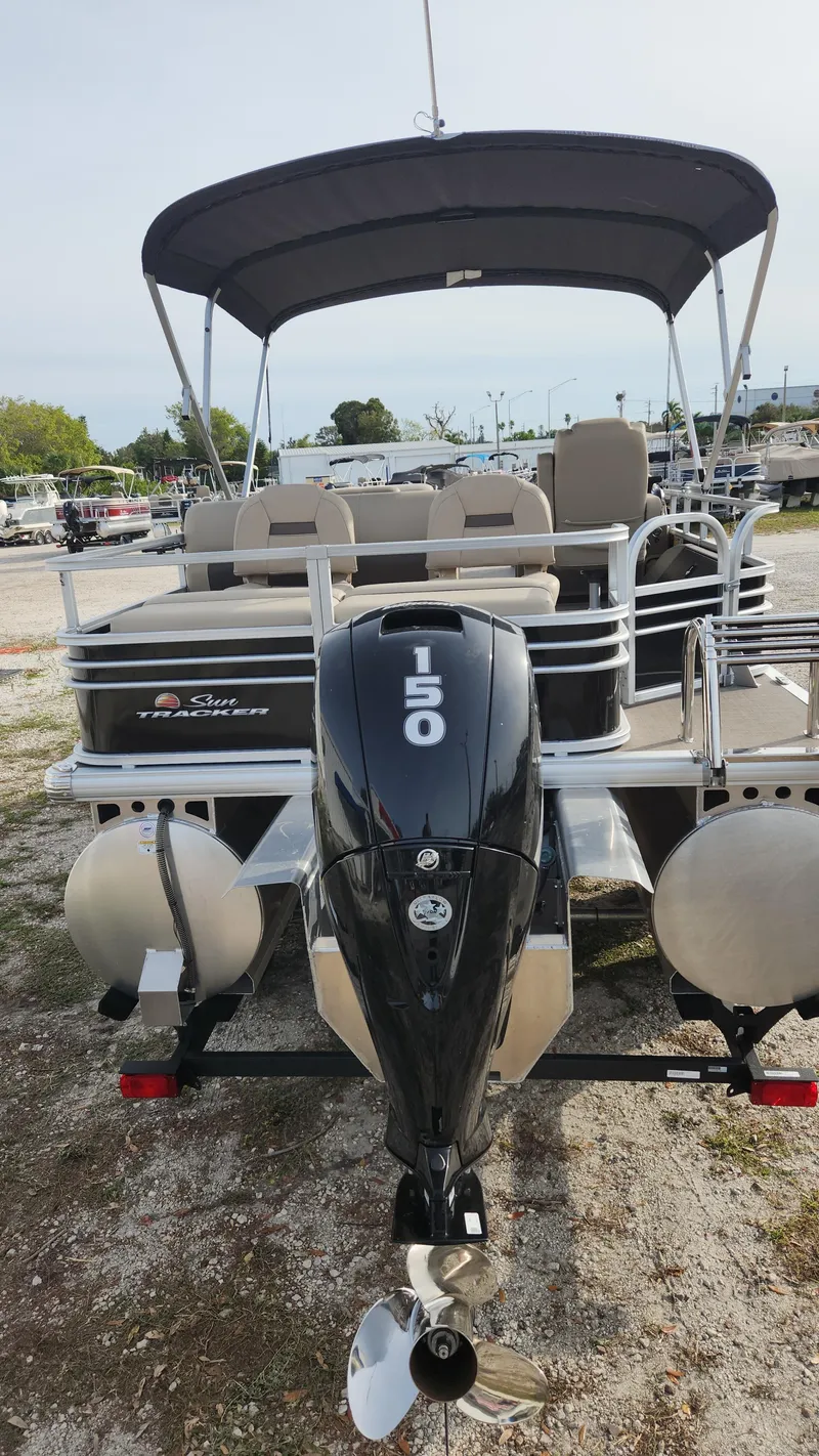 Slide: The Image of 2023 Sun Tracker SportFish 22 XP3 pontoon boat with 150 HP engine, docked outdoors. - 2