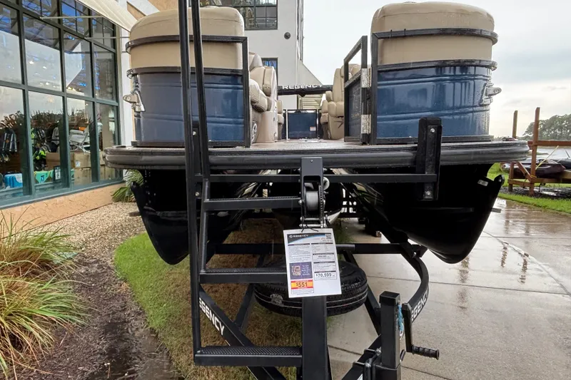 Slide: The Image of 2023 Regency 230 LE3 pontoon boat on trailer, displayed outdoors near a building. - 1