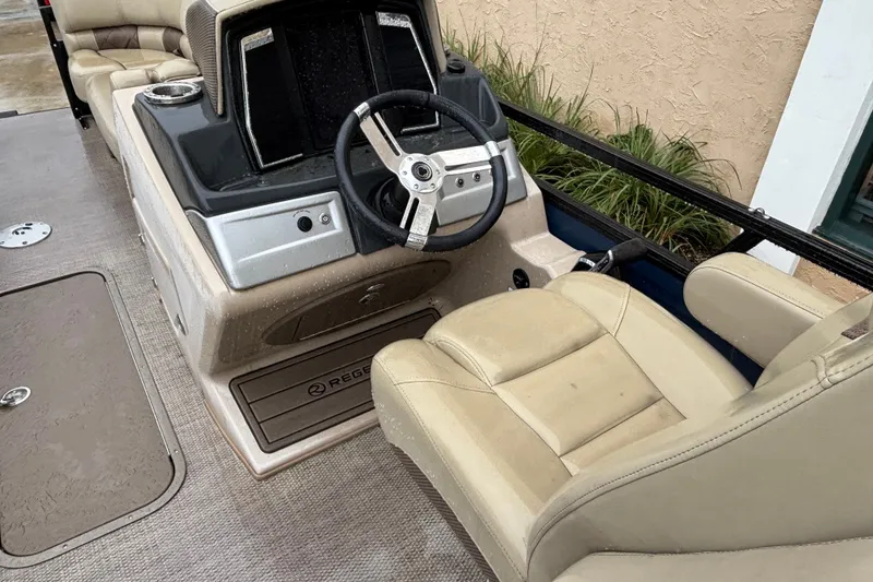Slide: The Image of 2023 Regency 230 LE3 boat interior with steering wheel and beige seating. - 6