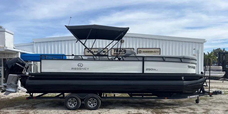 The Image of 2023 Regency 250 DL3 pontoon boat on a trailer outside a dealership. - 0