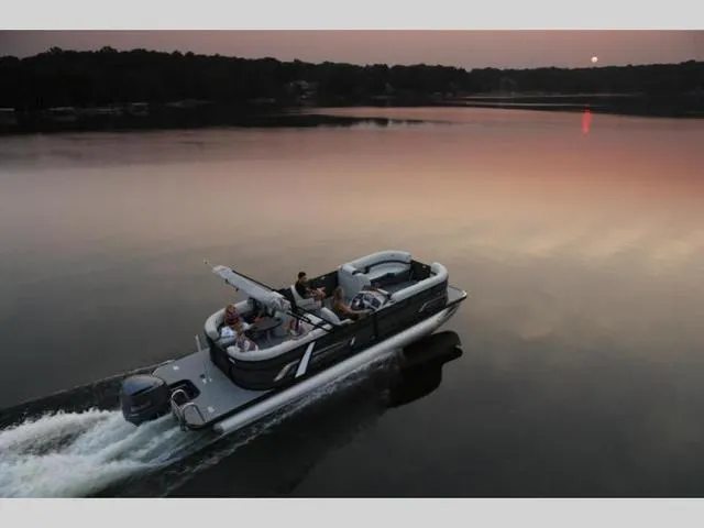 The Image of 2023 Starcraft EXS3 pontoon boat cruising on a serene lake at sunset. - 1