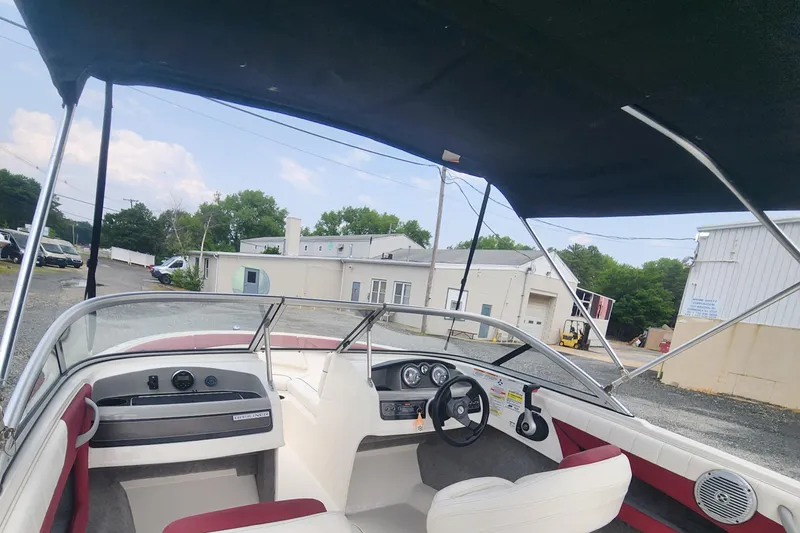 Slide: The Image of 2018 Bayliner 185 Bowrider interior with steering wheel and dashboard, parked outdoors. - 12