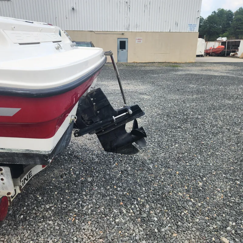 Slide: The Image of 2018 Bayliner 185 Bowrider boat rear view with outboard motor in a gravel lot. - 17