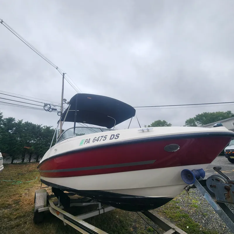 Slide: The Image of 2018 Bayliner 185 Bowrider boat on a trailer under a cloudy sky. - 19